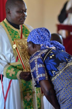 Kenyan priest holding the Gospel as the faithful venerate