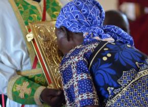 Kenyan priest holding the Gospel as the faithful venerate